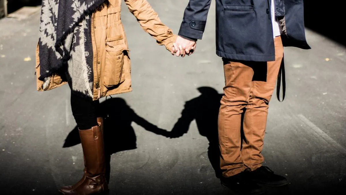 Casal de mãos dadas na rua durante um encontro presencial após meses de relacionamento à distância